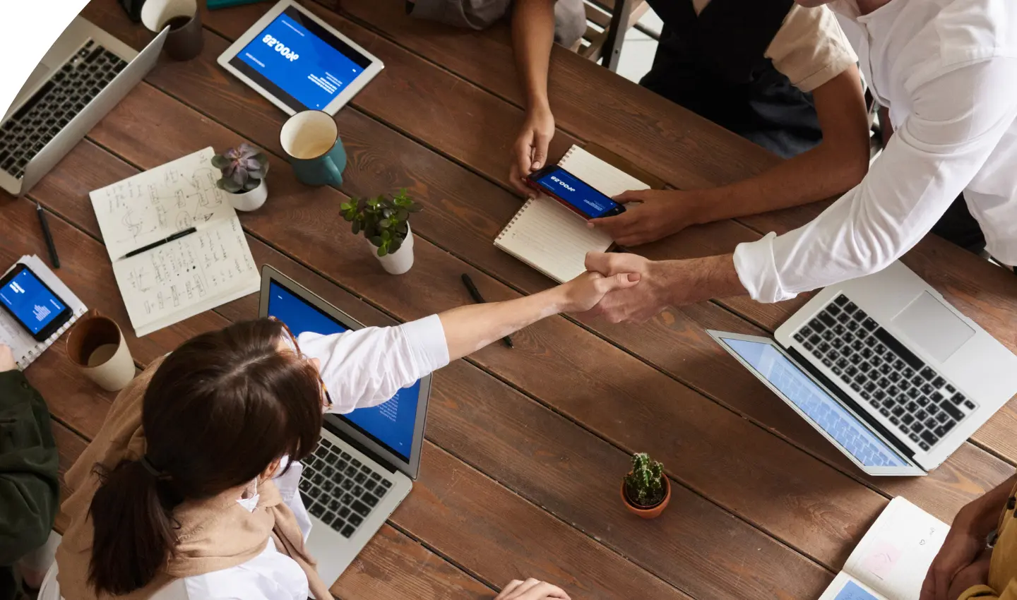 People in a business meeting shaking hands at a table, used for the Contact Us page